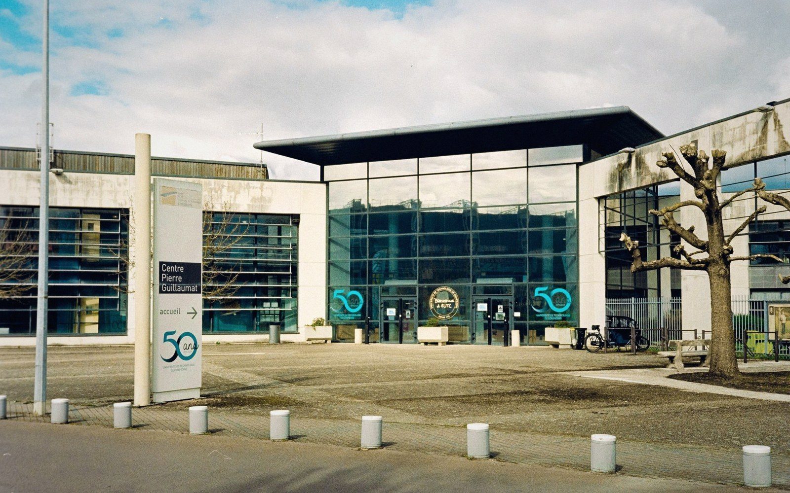 Glass-fronted entrance of the Centre Pierre Guillaumat building with a bare tree outside