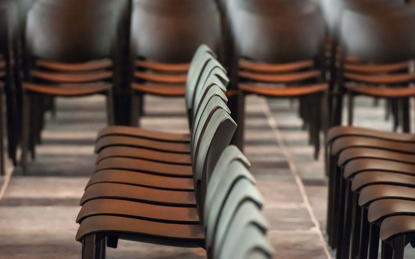 Folded temporary seating stacked in a venue service corridor under strip lighting after an event